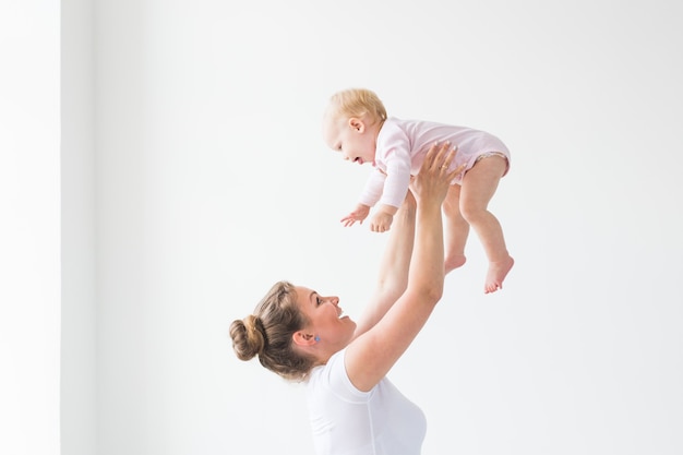 Heureuse jeune mère soulevant un bébé mignon en l'air, passer du temps avec sa fille.