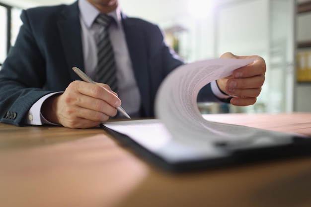 L'homme d'affaires met la signature sur le contrat assis à table dans le bureau Le PDG de l'entreprise vérifie