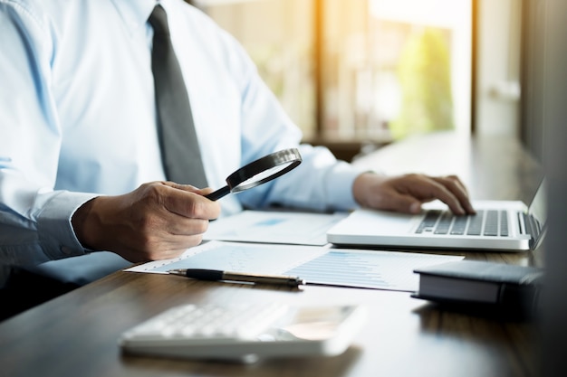 Homme d&#39;affaires travaillant au bureau avec des documents de données ordinateur portable, tablette et graphique sur son bureau