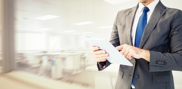 Homme d'affaires utilisant son tablet pc contre une salle de classe vide