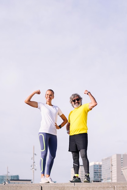 Photo un homme âgé et son entraîneur posent pour fléchir un muscle.