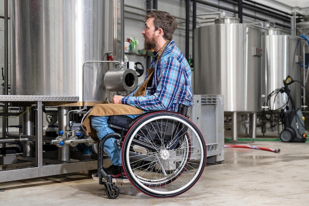 Homme en fauteuil roulant travaillant dans l'usine de la brasserie