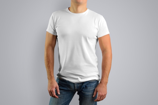 L'homme en t-shirt blanc est isolé sur un mur gris