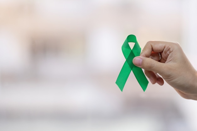 Homme tenant un ruban vert pour soutenir les personnes vivant et malades. Foie, vésicule biliaire, canal biliaire, concept de mois de sensibilisation au cancer du rein et au lymphome