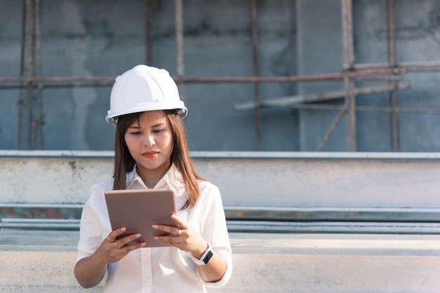 Ingénieur civil de femme asiatique avec un chantier de construction de casque de sécurité blanc.