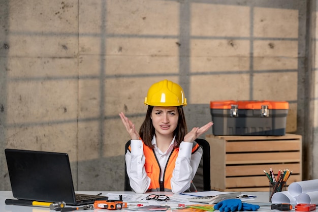 Ingénieur jeune jolie fille brune intelligente travailleur civil en casque et gilet confus