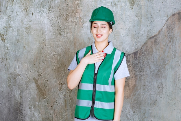 Photo ingénieur en uniforme vert et casque ressentant de la gratitude.