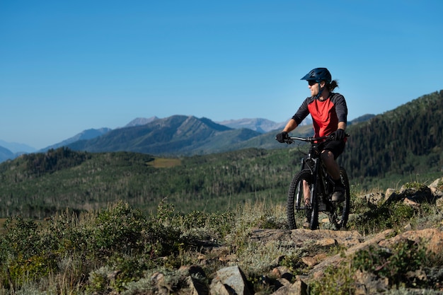 Photo jeune adulte à l'aide de vélo électrique à la campagne