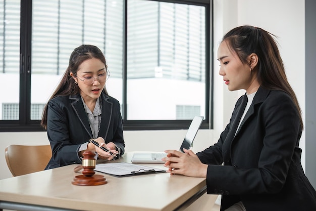 Photo un jeune avocat conseille une jeune femme dans un bureau moderne avec des documents juridiques et un marteau sur le bureau