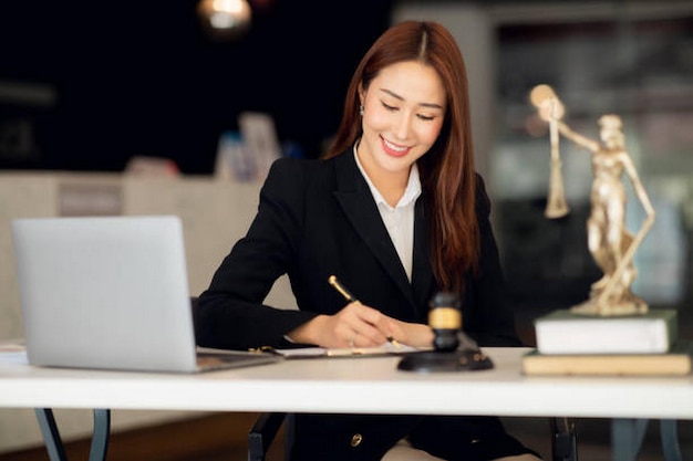 Photo une jeune avocate attrayante dans un bureau une femme d'affaires et des avocats discutent de documents contractuels avec une balance en laiton sur un bureau en bois dans un bureau conseil juridique sur les services juridiques concept de justice et d'immobilier