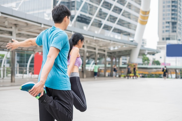 Photo jeune couple portant des vêtements de sport avec exercice d'étirement dans la ville