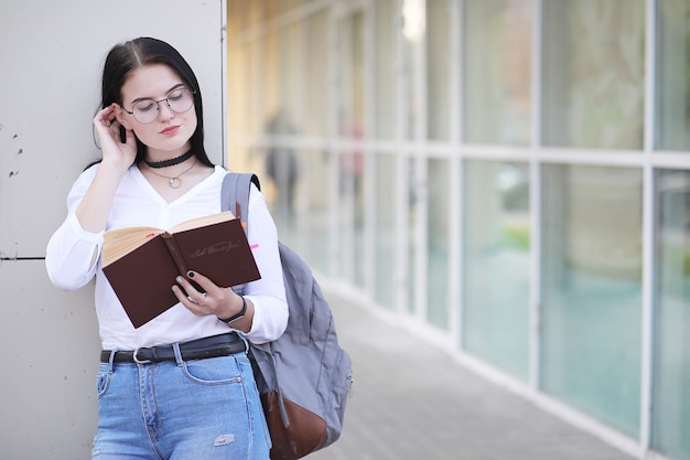 Photo jeune étudiante dans la rue avec un sac à dos et des livres