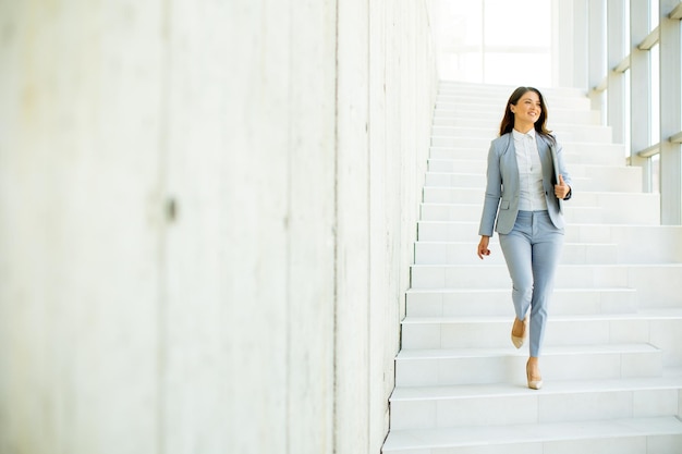 Jeune femme d'affaires marchant dans les escaliers et tenant un ordinateur portable