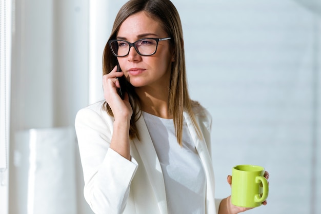 Jeune femme d&#39;affaires en utilisant son téléphone portable au bureau.