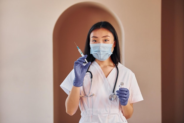 Jeune femme asiatique sérieuse debout à l'intérieur