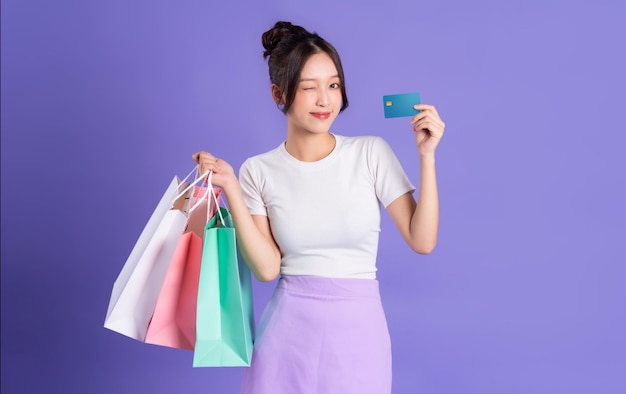 Jeune femme asiatique tenant un sac à provisions sur fond violet