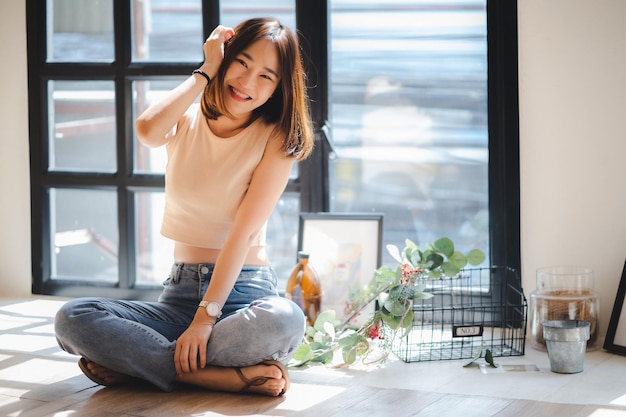 Photo une jeune femme assise à la fenêtre de sa maison.