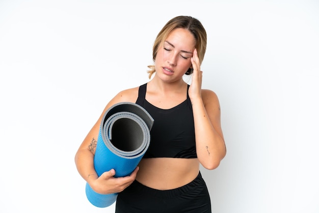 Jeune femme caucasienne allant à des cours de yoga tout en tenant un tapis isolé sur fond blanc avec des maux de tête