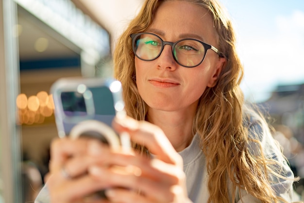 Jeune femme dans un café lisant un SMS depuis son téléphone portable