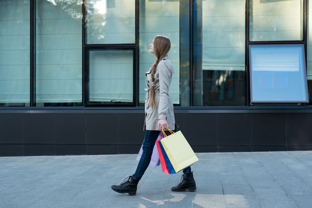 Jeune femme avec des sacs colorés marchant dans la rue.