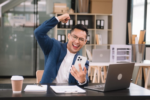 Photo jeune homme beau en train de taper sur une tablette et un ordinateur portable alors qu'il est assis à la table en bois de travail bureau moderne xa