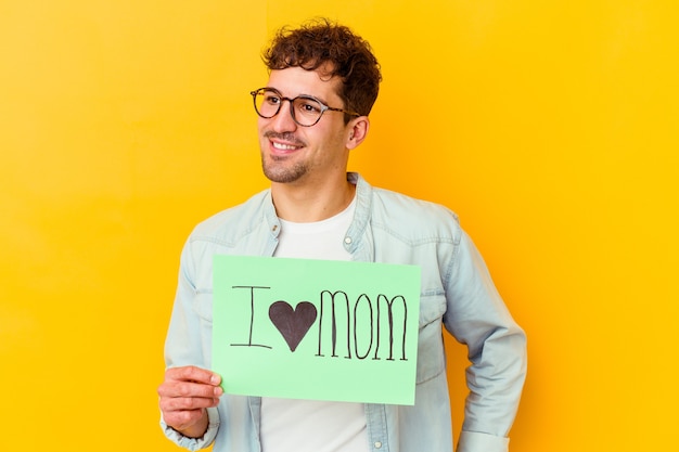 Jeune homme tenant une pancarte protéger notre planète isolé regarde de côté souriant, joyeux et agréable