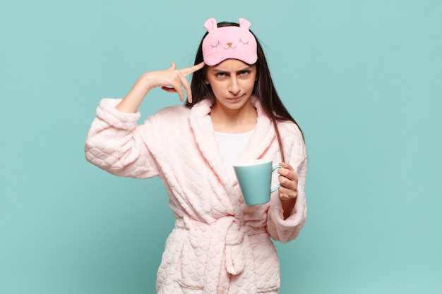 Jeune jolie femme se sentant confuse et perplexe, montrant que vous êtes fou, fou ou fou. concept de réveil en pyjama