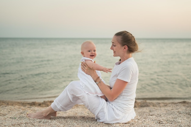 Jeune mère jouant avec bébé sur la plage Vacances avec de jeunes enfants en mer