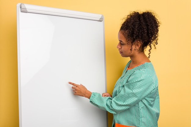 Jeune professeur d'éducation des enfants afro-américain expliquant sur le tableau noir isolé