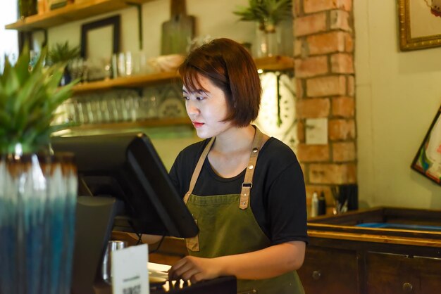 Photo une jeune serveuse vietnamienne travaillant avec un guichet automatique dans un café.