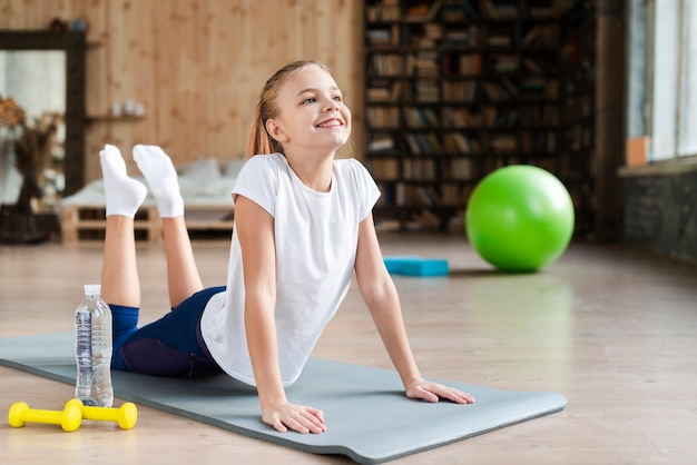 Jolie fille pratiquant le yoga sur tapis