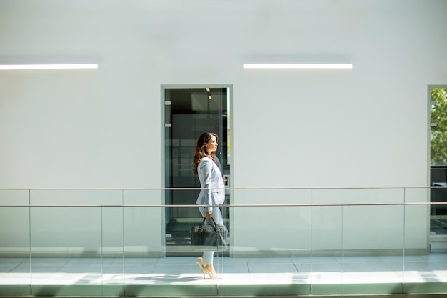 Jolie jeune femme d'affaires marchant avec une mallette dans le couloir du bureau