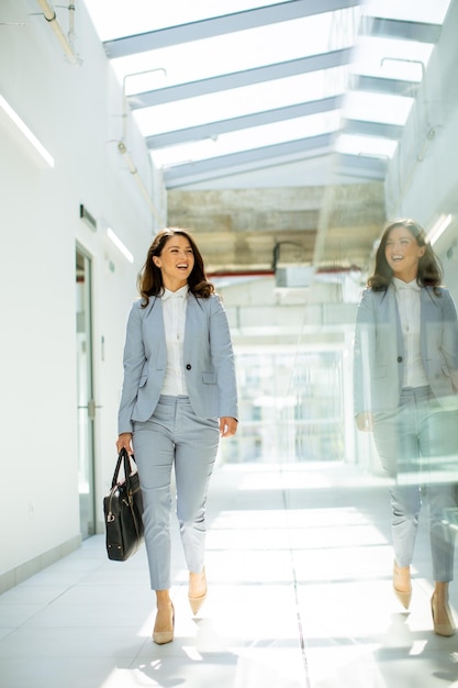 Jolie jeune femme d'affaires marchant avec une mallette dans le couloir du bureau