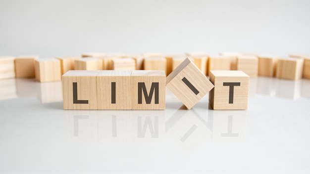 LIMITE - mot de blocs de bois avec des lettres sur fond gris. Reflet de la légende sur la surface réfléchissante de la table. Mise au point sélective.