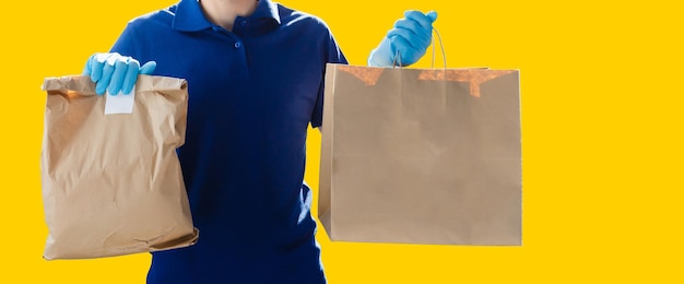 livreur transportant un sac en papier avec des produits alimentaires isolés sur fond jaune.