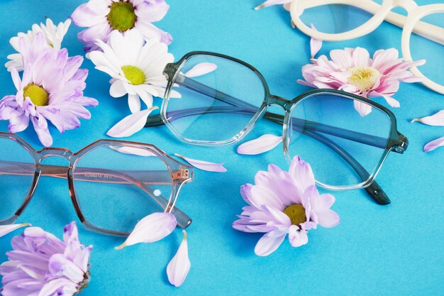 Lunettes à la mode et fleurs sur fond bleu