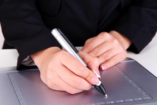 Photo main féminine à l'aide d'une tablette graphique sur la table en gros plan