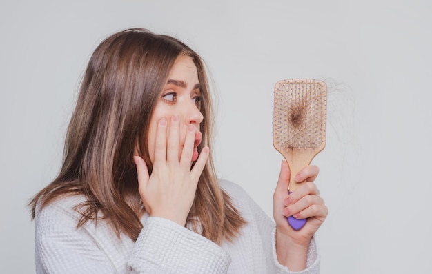 Main de femme tenant un peigne avec un grave problème de perte de cheveux pour le shampooing de soins de santé