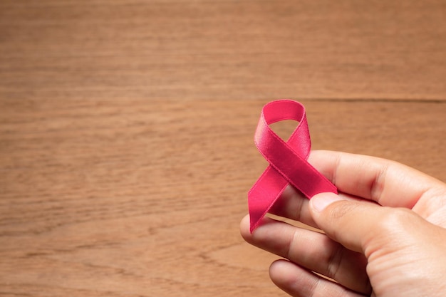 Main d'homme tenant un ruban rose pour la sensibilisation au cancer du sein