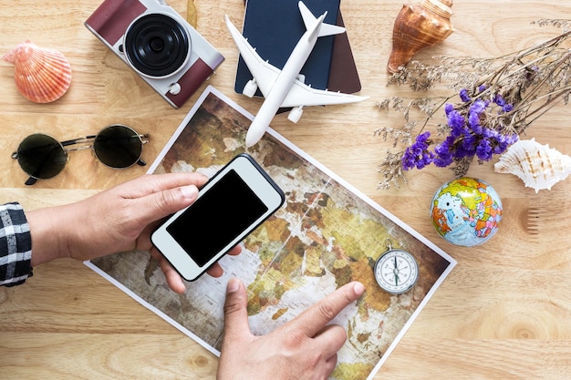 Photo des mains coupées d'un homme tenant un téléphone portable sur une carte à table