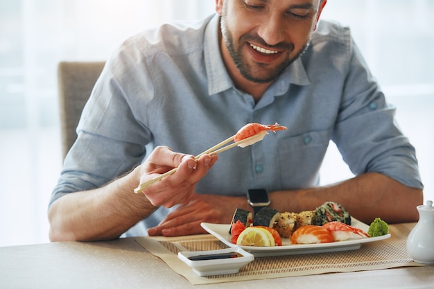 Meilleure nourriture meilleure humeur image recadrée d'un bel homme d'affaires souriant mangeant des sushis