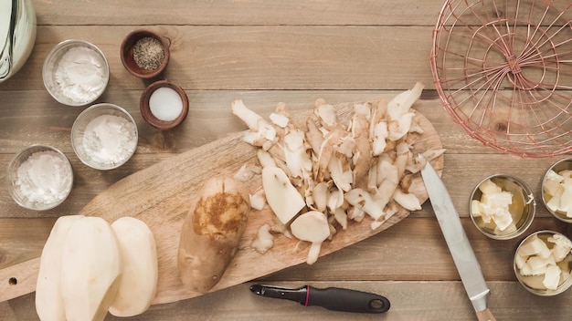 Mise à plat. Éplucher les pommes de terre jaunes biologiques avec un éplucheur de pommes de terre.