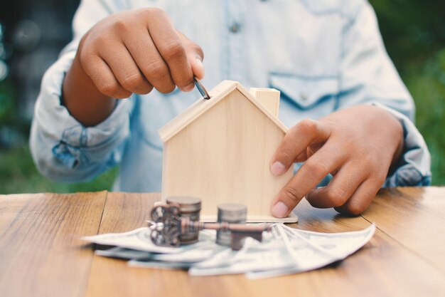 La moitié d'une femme mettant une pièce dans une maison modèle sur la table