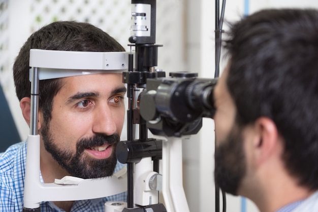 ophtalmologiste médecin vérifie la vision de beau jeune homme dans une clinique moderne