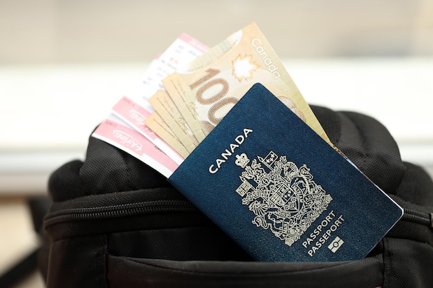 Photo passeport canadien et billets en dollars avec des billets d'avion sur le sac à dos en gros plan