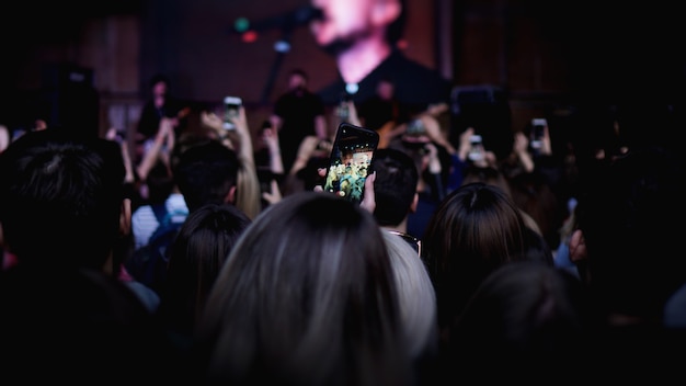 Photo personnes prenant des photos avec un smartphone tactile lors d'un concert public de divertissement musical. public au festival de musique en plein air