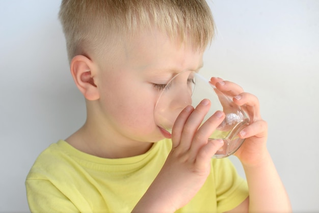 petit garçon boit de l'eau d'un verre