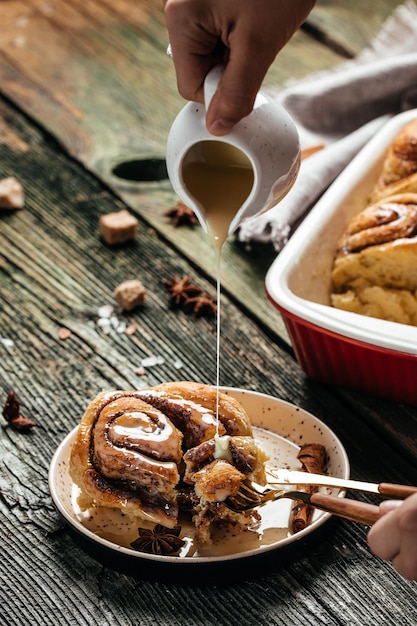 Petits pains au sinnabon. Crème à la vanille à la main de femme