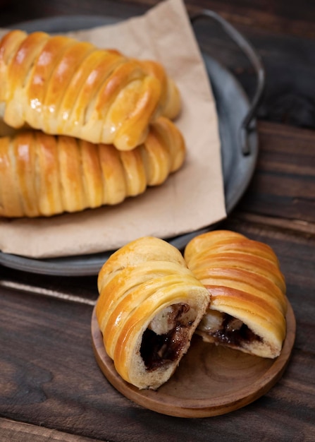 Petits pains sucrés fourrés au chocolat, fromage, bananes servis dans une assiette vintage en fer. Fond sombre.