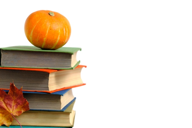 Pile de vieux livres de citrouille et d'automne feuillage jaunissé fond blanc